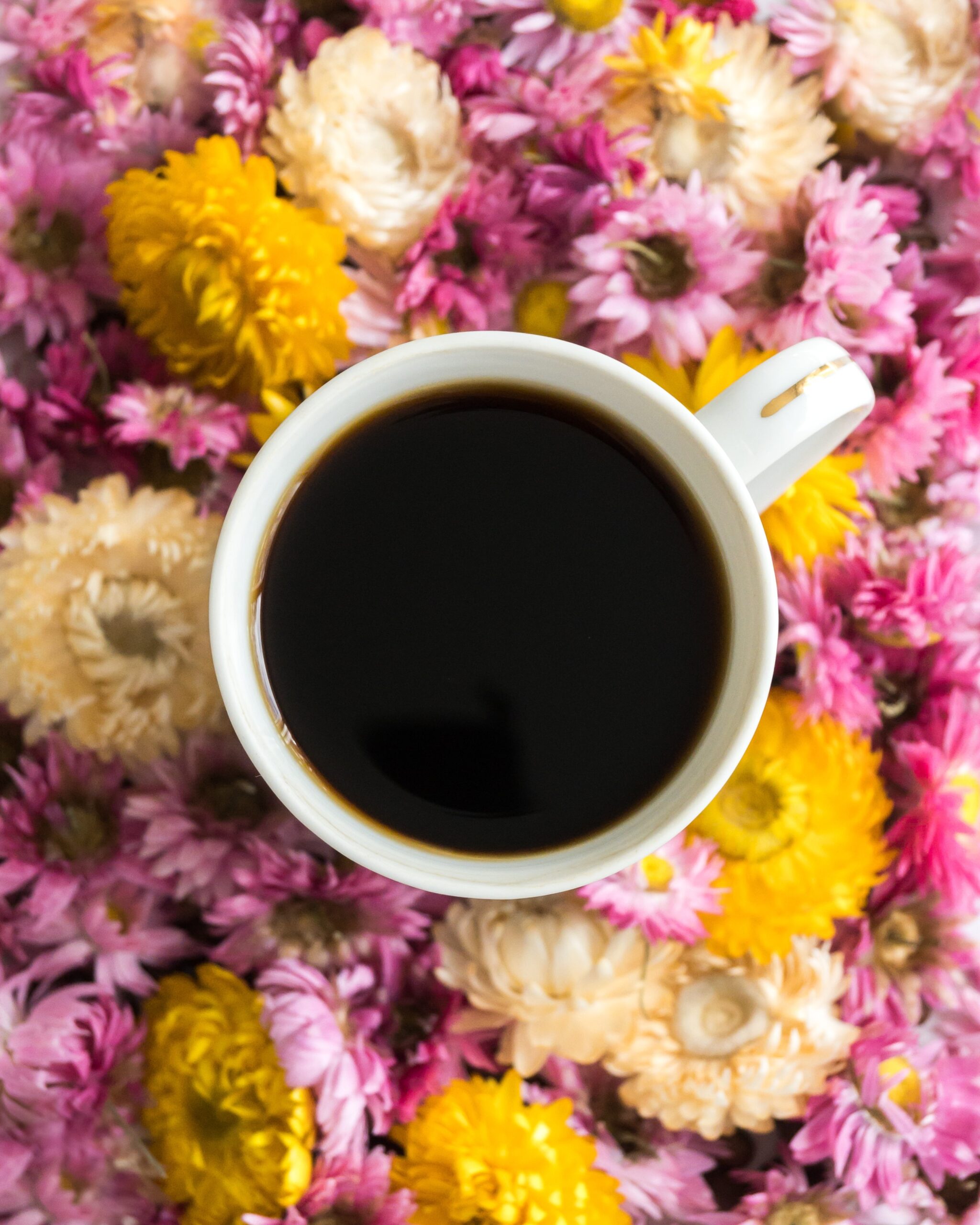 a cup of coffee sitting on top of a pile of flowers
